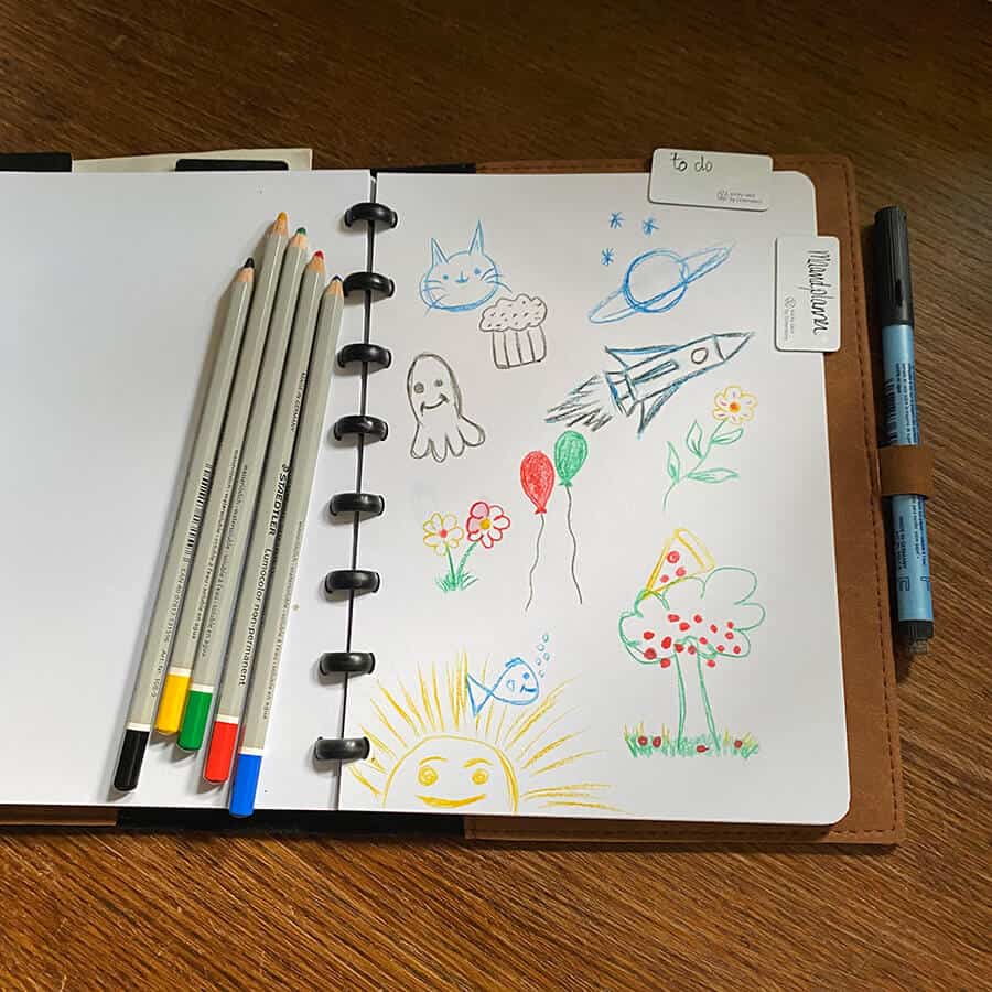 een productivity planner op een houten tafel met in doodle stijl getekende icoontjes door whiteboard potloden getekend