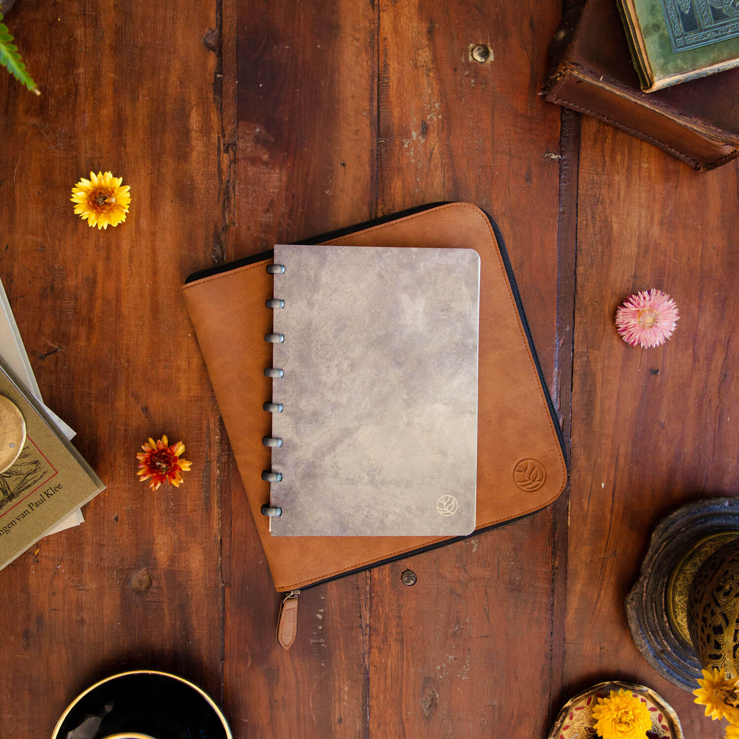 uitwisbaar notitieboek met concrete grey kaft en space grey ringen en een cognac werkmap platgelegd op een antiek houten tafel