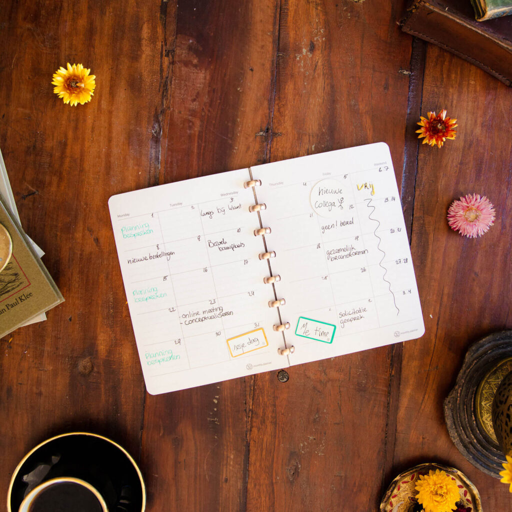 uitwisbaar notitieboek met uitwisbare maandplanner vellen platgelegd op een antiek houten tafel