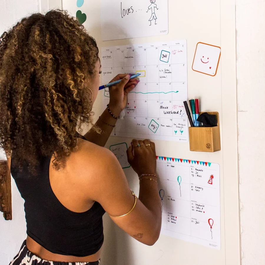 een dame schrijft op een sticky maandplanner met een whiteboard pen