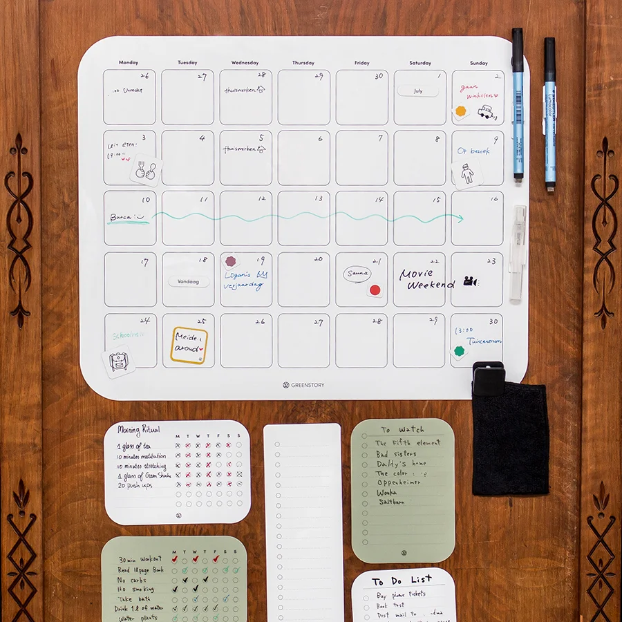 sticky maandplanner geplakt op een houten kast met sticky notes en een boodschappenlijstje